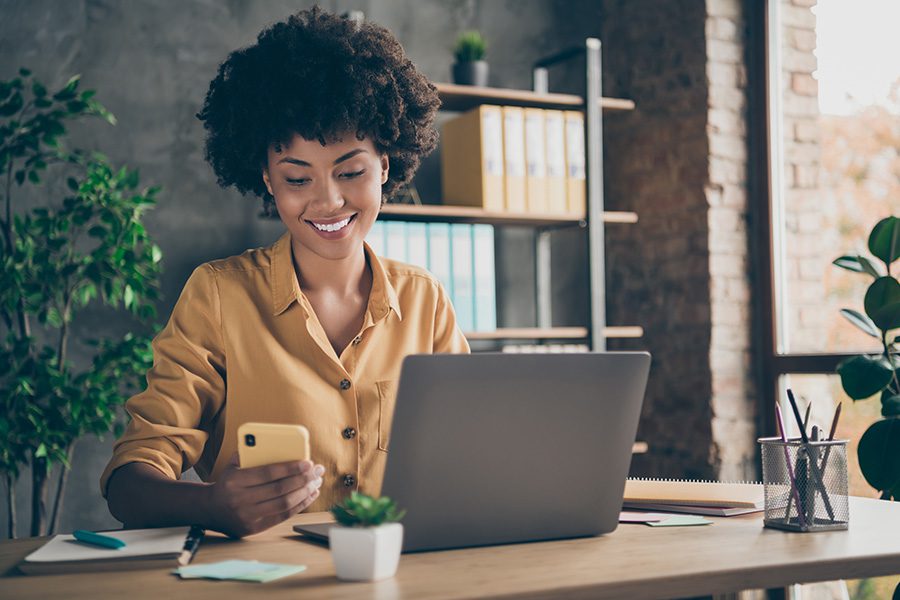 TURNER24 - Business Woman Working At Desk Looking At Her Mobile Phone Smiling